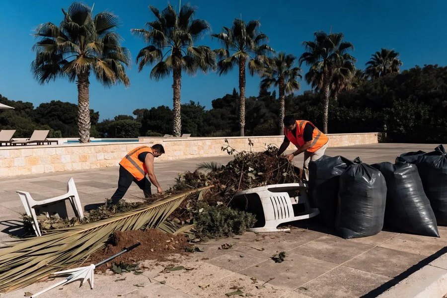 Paphos Junk Removals crew clearing garden waste and old furniture by a pool in Paphos